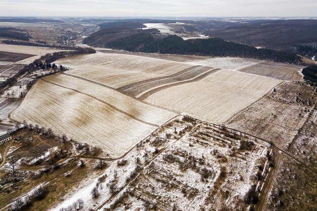 Vista superior de campos nevados vacíos y colinas boscosas en cielo nublado