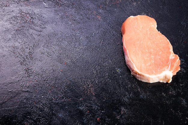 Vista superior de la carne cruda fresca sobre una mesa de madera negra. Comida gourmet y comida fresca sin cocinar