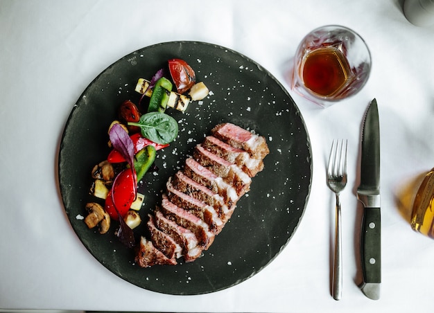 Vista superior de la carne de ternera tagliata con verduras asadas en placa negra