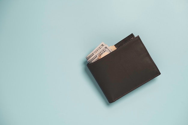 Vista superior de la cartera de dinero de cuero marrón con billete aislado en azul.