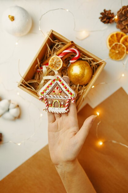 Vista superior de la casa de pan de jengibre de navidad en la caja de regalo de la mano con decoraciones festivas ...