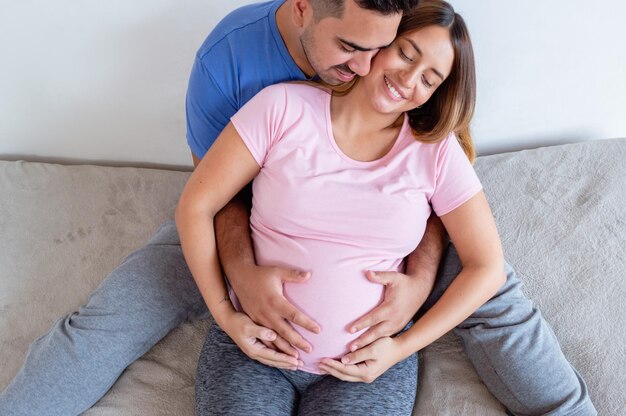 vista superior casal grávida abraçando sentado na cama