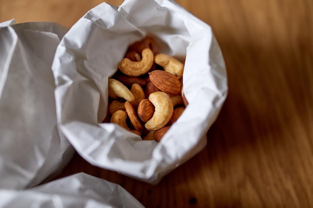 Vista superior castanha de caju e amêndoa na mesa em um saco de papel no fundo de madeira, compras, conceito de mercearia, entrega de nozes, desperdício zero, compras de alimentos, espaço de cópia