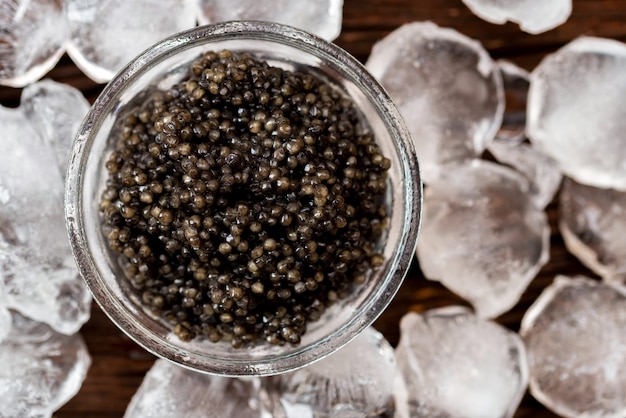 Vista superior del caviar de esturión negro en la mesa de madera