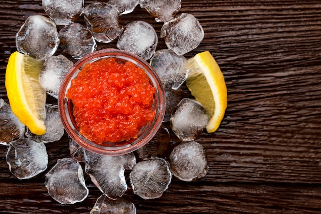 Vista superior del caviar de salmón rojo en la mesa de madera