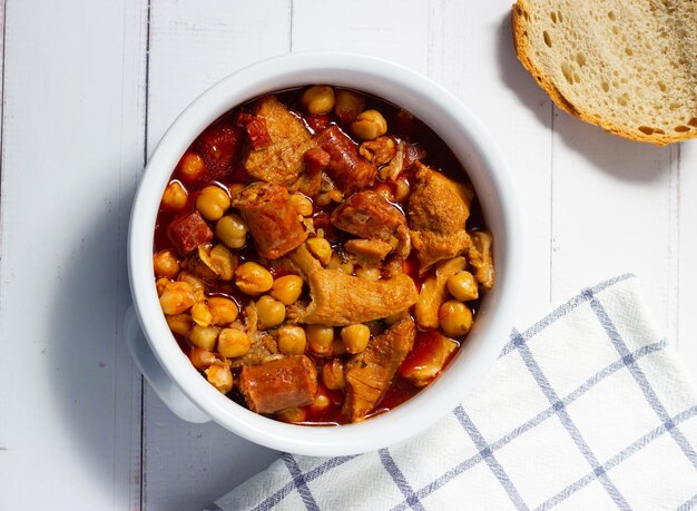 Vista superior de una cazuela de callos con garbanzos sobre un fondo blanco de madera Comida reconfortante de invierno Callos a la madrilena