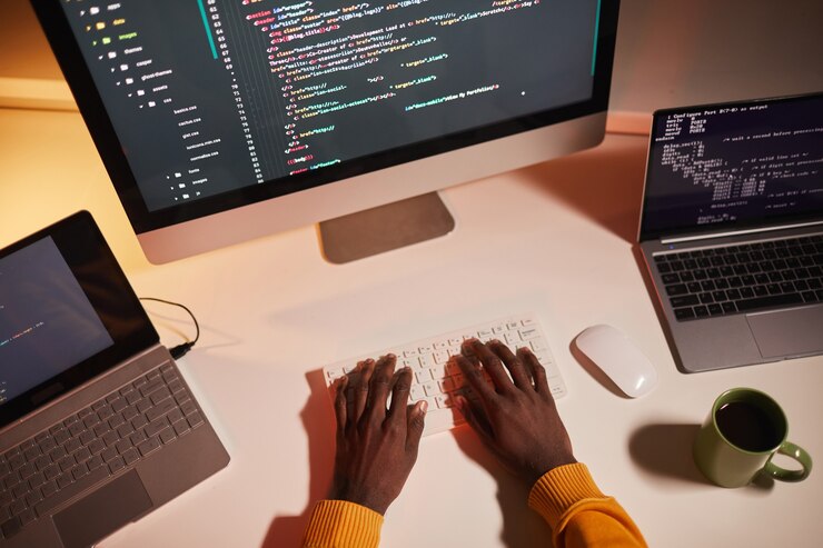 Foto vista superior de cerca del irreconocible hombre afroamericano escribiendo código mientras trabaja con varias pantallas de computadora, espacio de copia