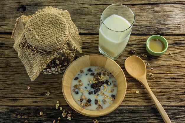 Vista superior del cereal y la leche, abeja de la miel en la tabla de madera vieja.