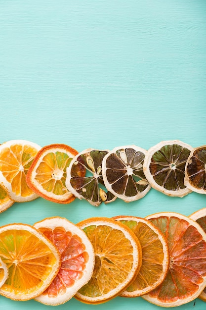 Vista superior de chips de cítricos secos naranja limón y pomelo sobre fondo turquesa