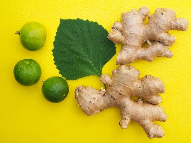 Foto vista superior de cítricos de jengibre y limón con hojas verdes sobre amarillo.