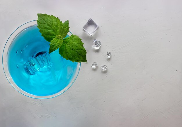 Foto vista superior de cóctel azul en copa de martini con cubitos de hielo y menta