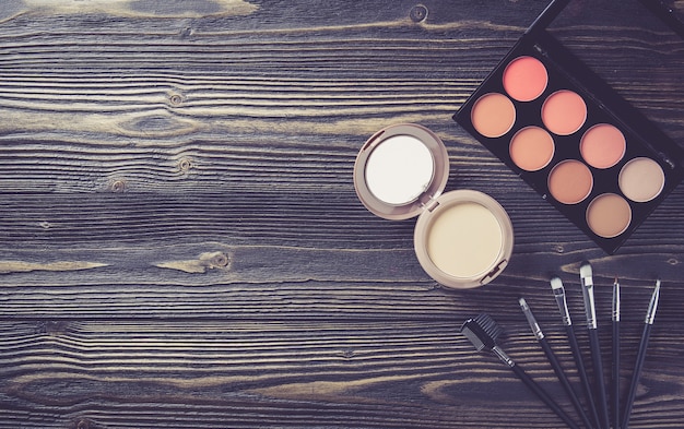 Foto vista superior de una colección de maquillaje cosmético en el fondo de la mesa de madera.