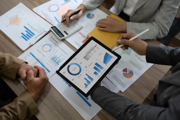 Vista superior de colegas de negocios en la oficina moderna analizando gráficos y gráficos de ingresos en tableta digital