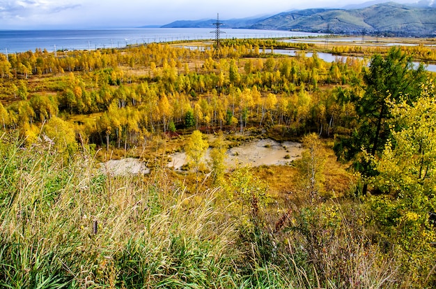 Una vista superior de coloridos árboles forestales y lago en la temporada de otoño. Escena del lago Baikal, Rusia