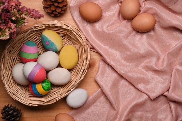 Vista superior coloridos huevos de Pascua en cesta de mimbre sobre mesa de madera Concepto de éster