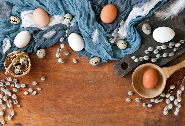 Vista superior de coloridos huevos de Pascua y huevos de codorniz, sauces y plumas.