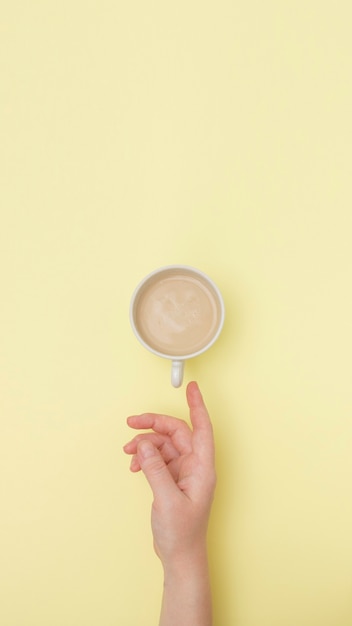 Vista superior com mãos segurando uma xícara branca de cappuccino