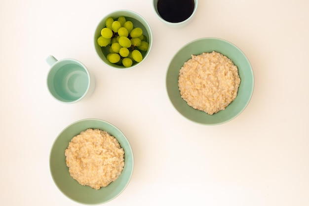 Vista superior de la comida de la mañana sobre fondo blanco Avena con taza de café porrige de la mañana con uva