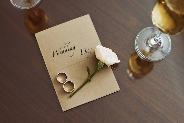 Vista superior de la composición de la boda que consiste en una rosa de invitación y dos anillos