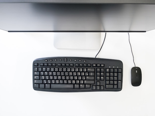 Vista superior de la computadora de escritorio con el teclado y el ratón sobre fondo blanco.