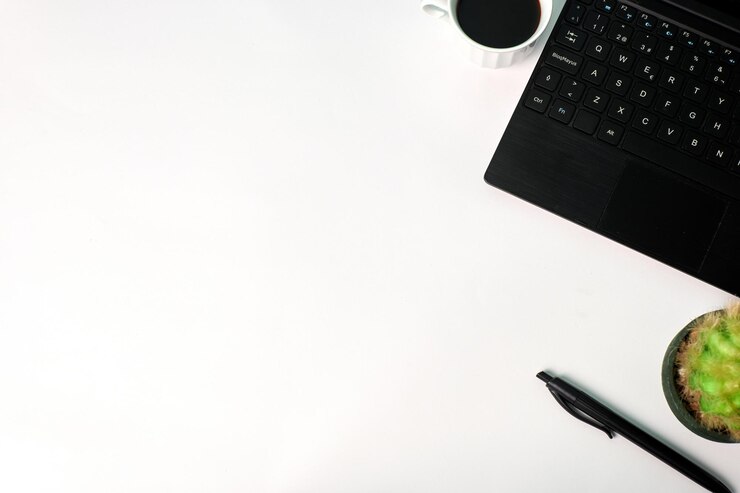 Vista superior de una computadora portátil, un bolígrafo, una planta y una taza de café sobre un fondo blanco. Copie el espacio, concepto de negocio