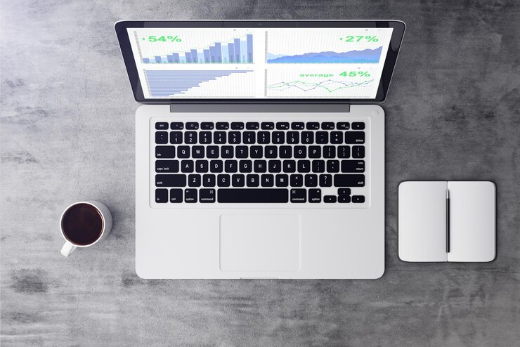 Foto vista superior de la computadora portátil con estadísticas financieras en la pantalla con taza de café y diario