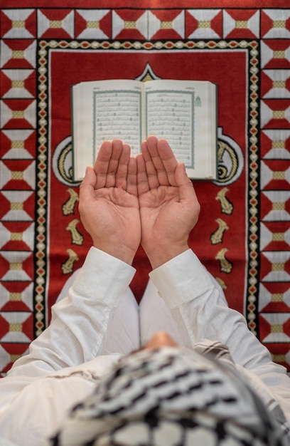 Vista superior conceito namaz homem muçulmano rezando em frente ao Alcorão em um tapete de oração Ramadã no islã