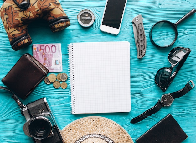 Vista superior de conjunto de accesorios de viaje sobre fondo azul de madera con espacio de copia