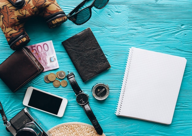 Vista superior de conjunto de accesorios de viaje sobre fondo azul de madera con espacio de copia