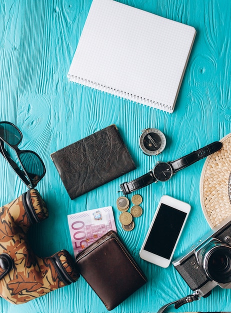 Vista superior de conjunto de accesorios de viaje sobre fondo azul de madera con espacio de copia