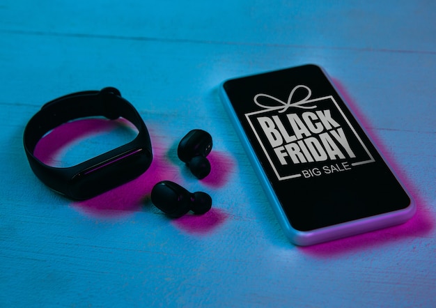 Foto vista superior del conjunto de gadgets en luz de neón púrpura, fondo azul. smartphone, relojes inteligentes, auriculares. tecnología, moderno, gadgets, publicidad. black friday, cyber monday, ventas, finanzas concepto de compras en línea