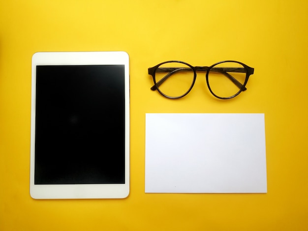 Foto vista superior de un conjunto simple de escritorio de trabajo amarillo con bloc de notas, glases y bloc de notas.