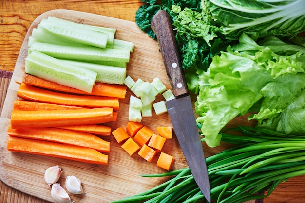 Vista superior del conjunto de vegetales de zanahorias y pepinos en rodajas, ajo, cebolla verde y lechuga