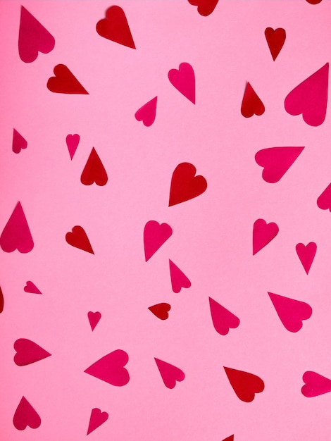 Vista superior de corazones de papel rojo y rosa sobre superficie rosa