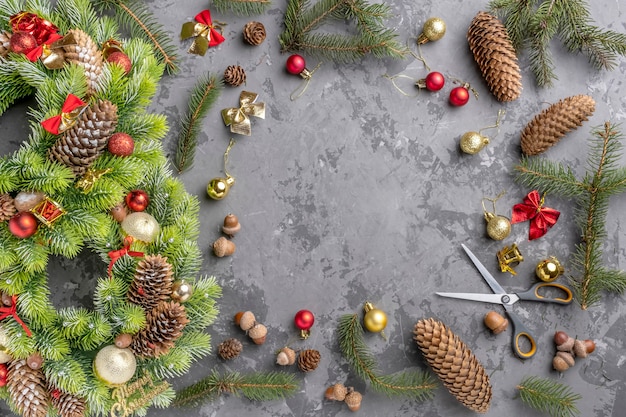 Vista superior de la corona de Navidad con abeto, piñas, bolas y cintas sobre superficie de hormigón