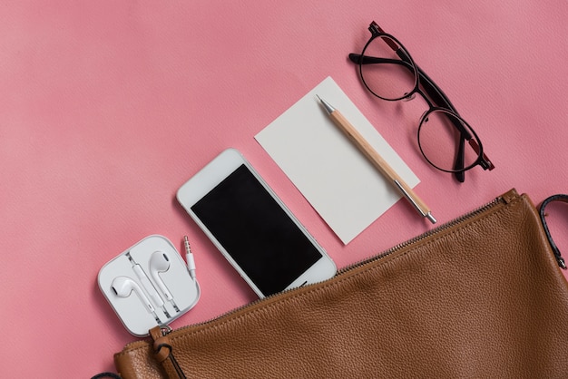 Vista superior de cosas de mujer hipster travller con teléfono, bloc de notas, gafas y auriculares