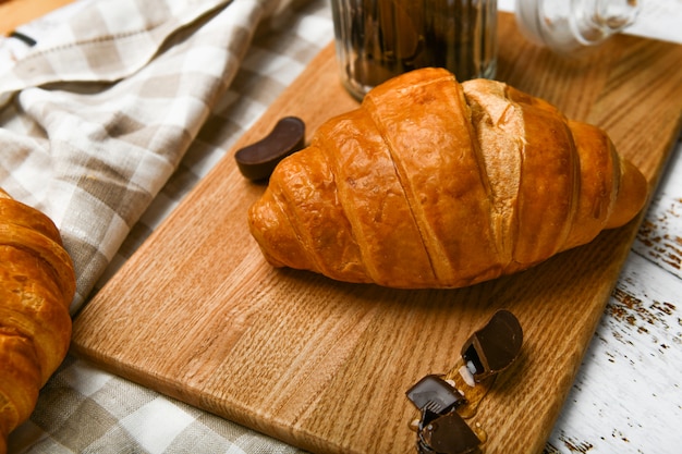 Vista superior de croissants de chocolate francés. El comienzo de la mañana. Croissant francés fresco. Taza de café y cruasanes recién horneados en una madera. .