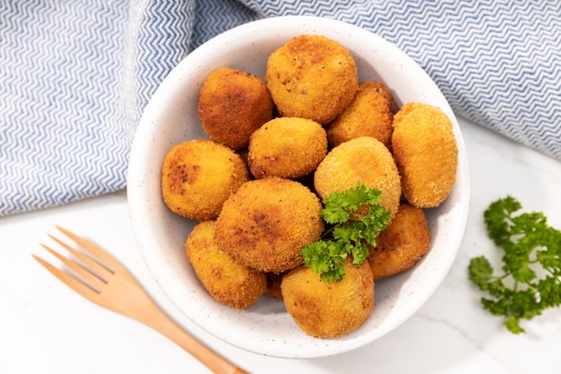 Vista superior de croquetas caseras en una servilleta de cerámica y tenedor sobre mesa de mármol blanco