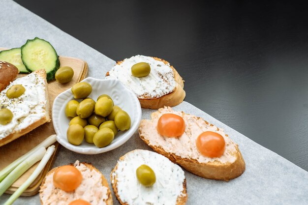 Vista superior de una crujiente baguette rebanadas con tomates cherry, pepinos y aceitunas verdes, queso crema.