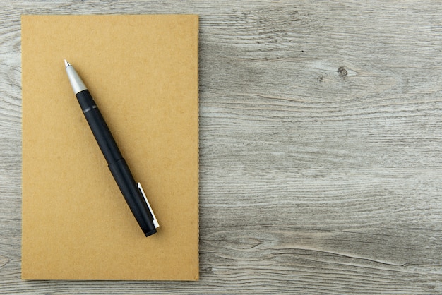 Vista superior del cuaderno con el escritorio blanco con fondo de pluma estilográfica