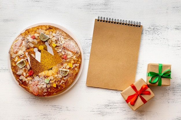 Foto vista superior del cuaderno con postre y regalos para el día de la epifanía.