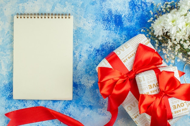 Vista superior del cuaderno de regalos del día de San Valentín flores sobre fondo azul.