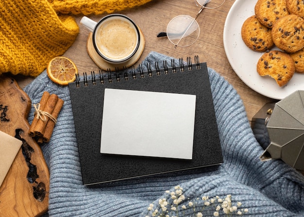 Vista superior del cuaderno en suéter con galletas y taza de café