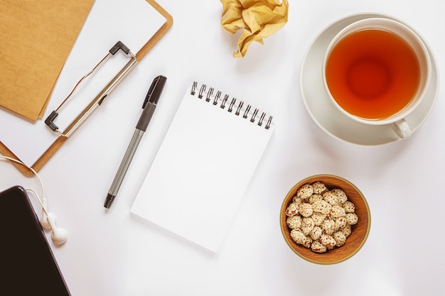 Vista superior del cuaderno, taza de té y portapapeles en el escritorio