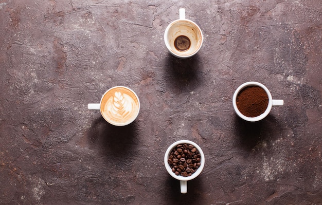 Vista superior de cuatro tazas de diferentes etapas de preparación de capuchino con espacio de copia, forma de reloj, tiempo para el café