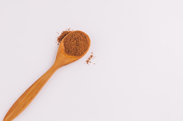 Vista superior de una cuchara de madera de sándalo con canela sobre fondo claro