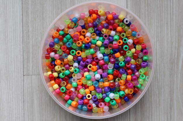 Vista superior de cuentas de plástico multicolores en un recipiente de plástico en una mesa