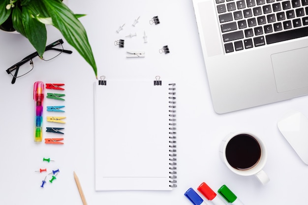 Vista superior da área de trabalho com um caderno branco com espaço livre para texto no centro