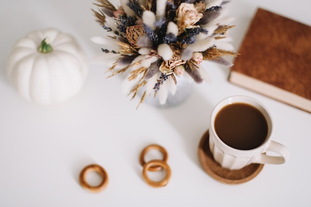 Vista superior da área de trabalho ou mesa de escritório com uma xícara de café e flores sobre fundo branco