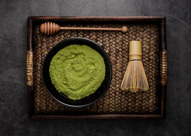 Vista superior da bandeja com matcha chá em pó na tigela com batedor de bambu